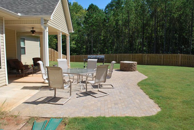 a backyard paver patio with a fire pit and garden furniture