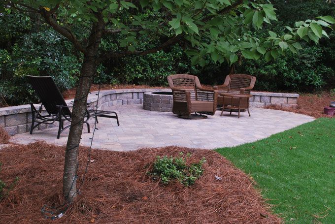 stone patio with a fire pit and a seat wall