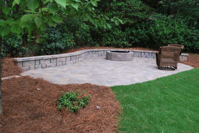 stone patio with a fire pit and a seat wall