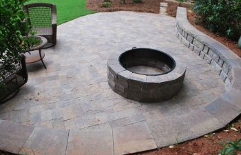 stone paver patio with a seat wall and a fire pit