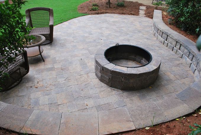 stone patio with a fire pit and a seat wall