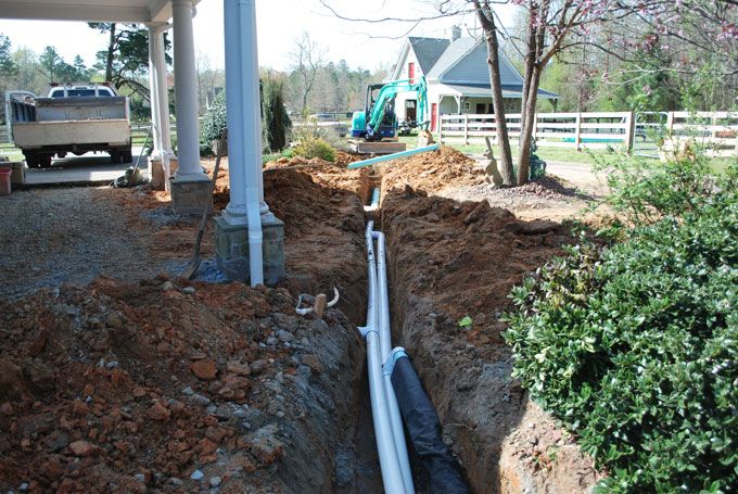 Installation of drainage systme combining gravel pits and downspout drains to handle both surface and gutter water.