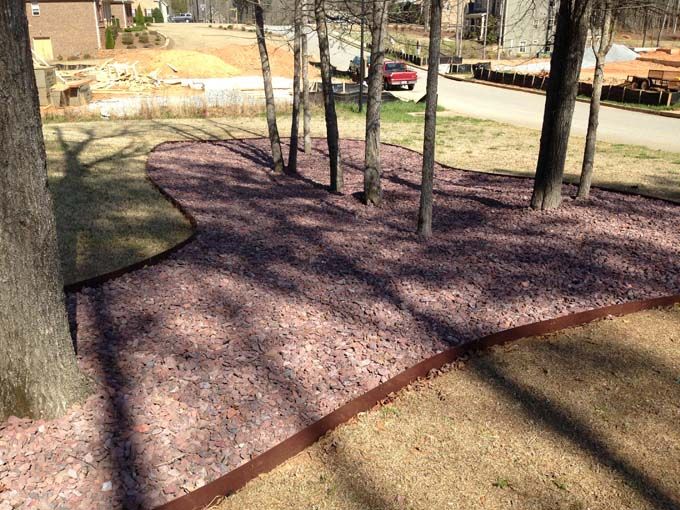 mulched spot with trees with raised edging separating it from a lawn