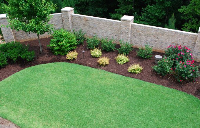 Thick zoysia sod contrasted against brown mulch with colorful plantings.