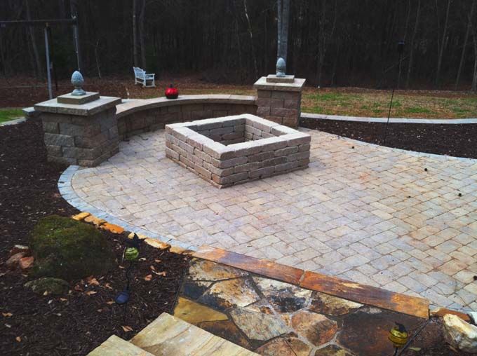 a paver stone patio with decorative seat wall and a fire pit