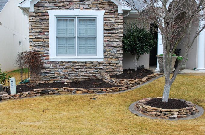 stack garden walls separating mulched areas with plants from a lawn