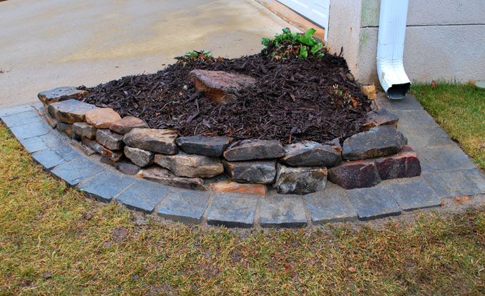 mulch with plants surrounded by dry stack garden wall with paver