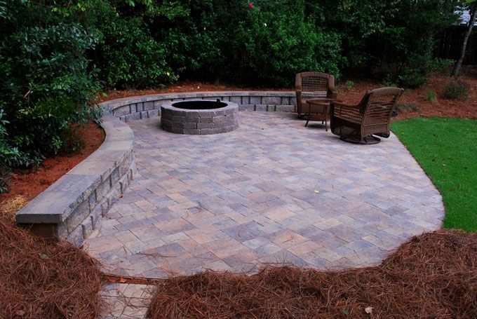 stone patio with a fire pit and a seat wall