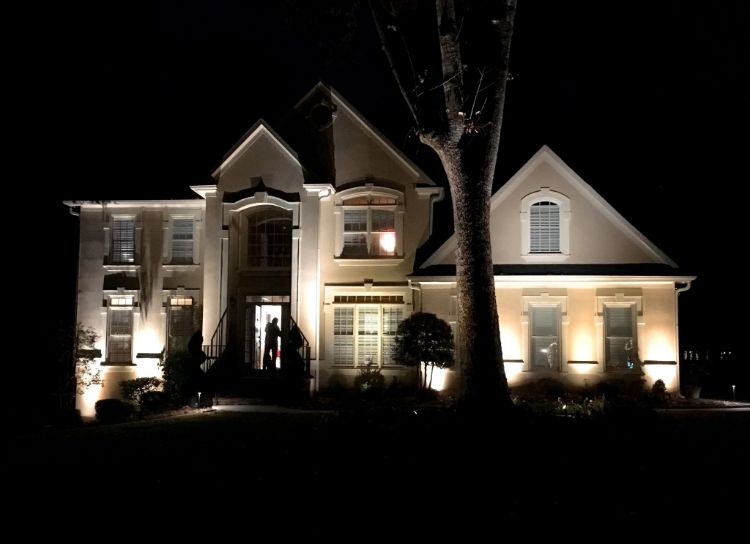 Landscape lights in front of the house creating light and shade patterns on the front wall