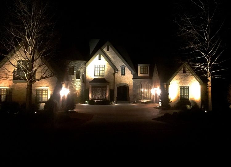 A house front and entrance lit by outdoor lights