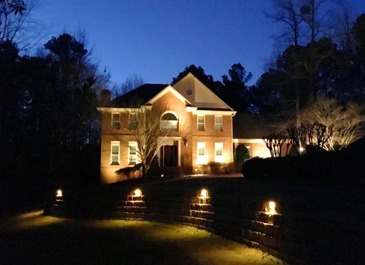 Landscape lights in front of the house creating light and shade patterns on the front wall