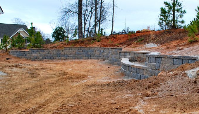 preparing ground for sod installation next to a new retaining wall