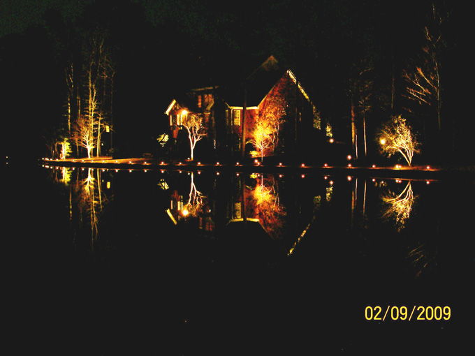 lakeside home with landscape lighting at night