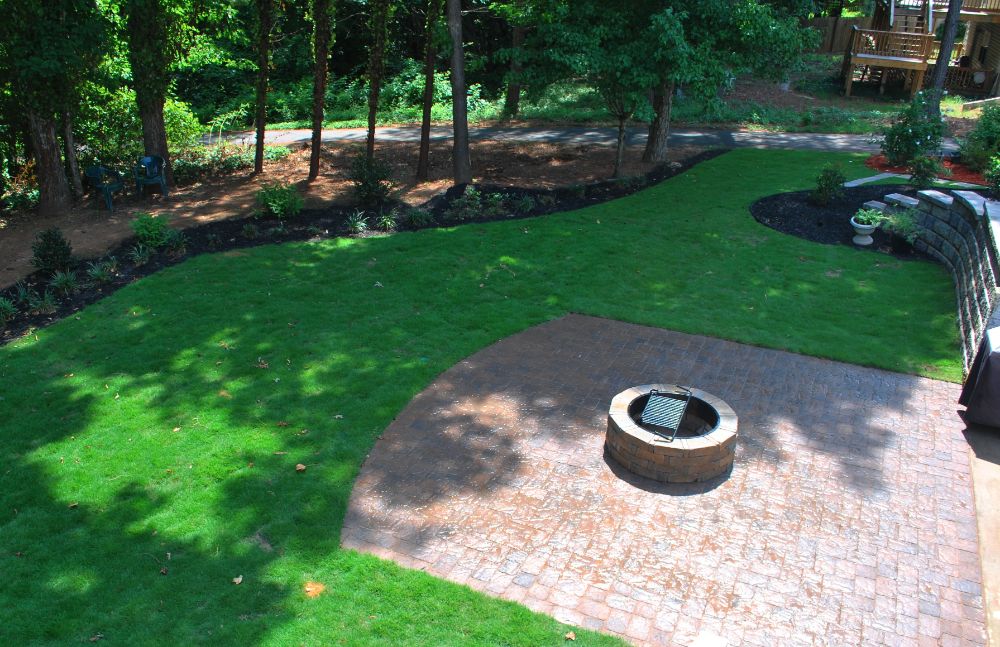 Patio with firepit surrounded by partially shade zoysia lawn.