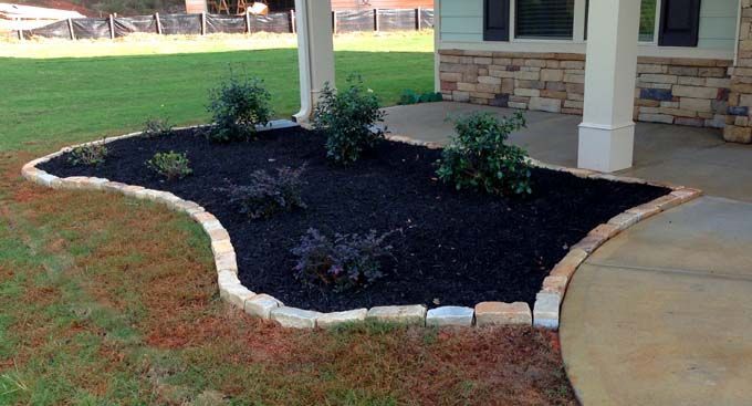 tumbled rock edging separating mulch and plants from a walkway and lawn